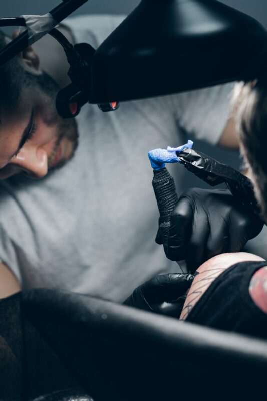 how to become a tattoo artist. tattoo artist. a tattoo artist tattooing the upper arm of a woman